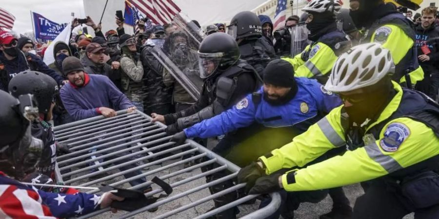 Trump-Anhänger versuchen am 6. Januar 2021, durch eine Polizeiabsperrung am US-Kapitol zu brechen. Foto: John Minchillo/AP/dpa