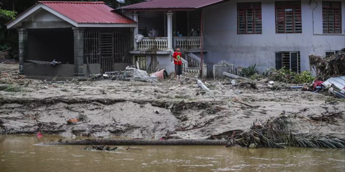 Ein Kind läuft über Schlamm vor einem Haus in Kuala Langat, Malaysia. Five killed and 41,000 displaced as floods hit several Malaysian states.