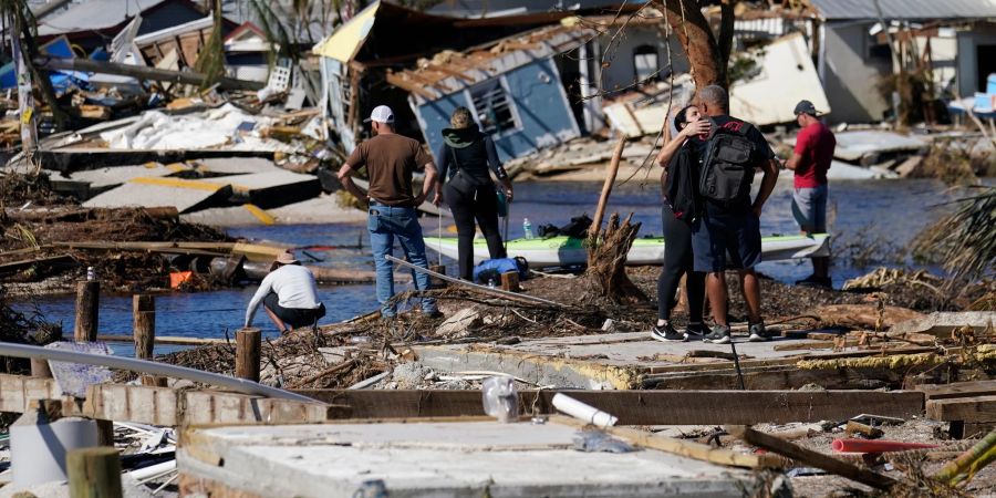 Menschen betrachten von einer zerstörten Brücke in Matlacha im US-Bundesstaat Florida aus die Schäden.