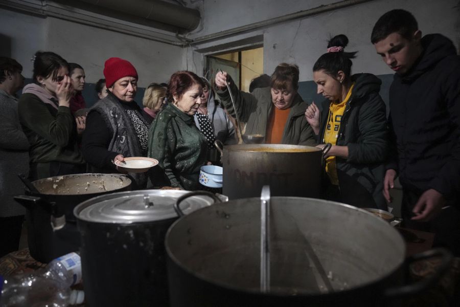 Menschen stehen in einem Bunker in Mariupol für warmes Essen an. (AP Photo/Evgeniy Maloletka)