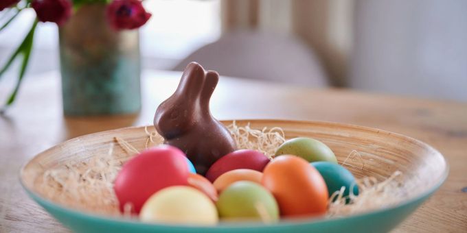 Ein ausgepackter Schokohase und gefärbte Eier. Ostern