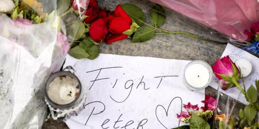 Blumen, Kerzen und eine Botschaft mit "Fight Peter" liegen am Tatort. Foto: Koen Van Weel/ANP/dpa