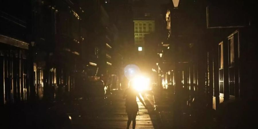 Eine Frau geht im Scheinwerferlicht eines patrouillierenden Polizeiwagens über die Bourbon Street in New Orleans. Foto: Eric Gay/AP/dpa