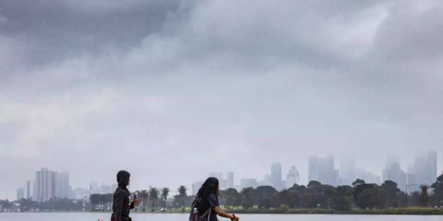 Menschen gehen mit einem Hund am Albert Park Lake in Melbourne spazieren. (Archivbild). Foto: Daniel Pockett/AAP/dpa