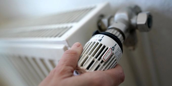 Eine Frau dreht an einem Heizungsthermostat. Eine Frau dreht an einem Heizungsthermostat.