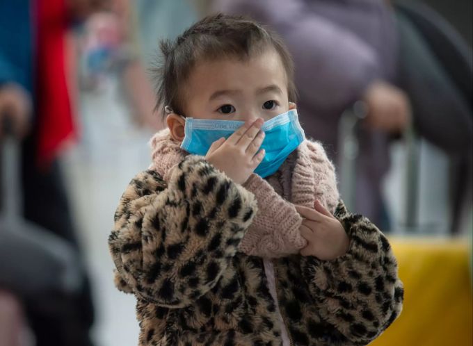 Zusammen mit ihrer Mutter wartet die kleine Tramy auf dem Flughafen Frankfurt am Check-In-Schalter einer vietnamesischen Fluggesellschaft. Dabei trägt sie eine Mundschutzmaske. Flugpassagiere mit Mundschutzmasken
