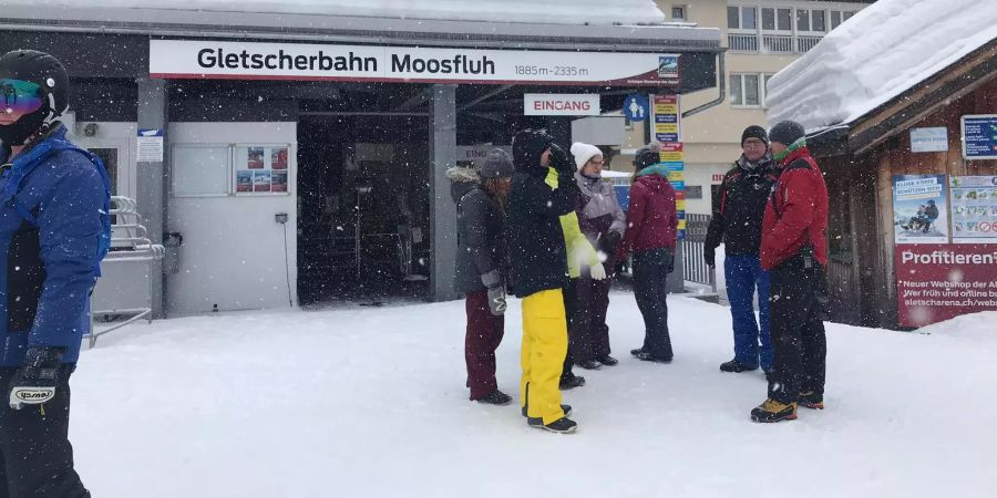 Wintersportler auf der Riederalp VS stehen vor der nicht laufenden Bahn.