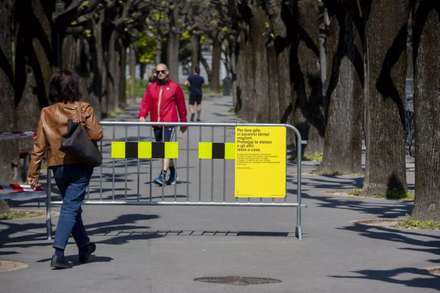 Menschen spazieren am Karfreitag beim Seeuferweg des Lago di Lugano in Lugano. Das Seeufer ist für Gruppen von mehr als 5 Personen wegen der Coronavirus-Pandemie geschlossen.