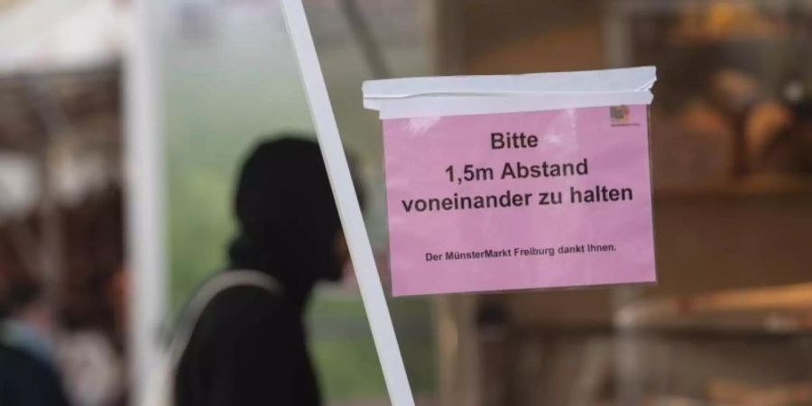 Ein Mann kauft auf dem Markt ein. Am Stand ist ein Schild angebracht mit der Aufschrift «Bitte 1,5 m Abstand voneinander zu halten». Foto: Patrick Seeger/dpa