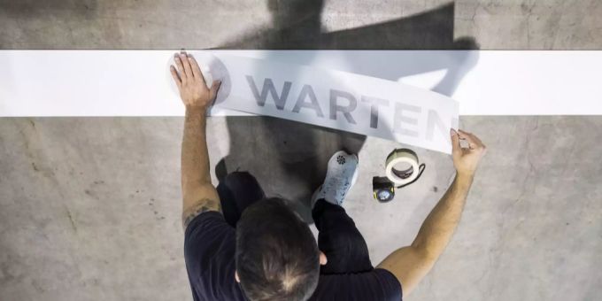 Ein Mitarbeiter befestigt einen Schriftzug mit der Aufschrift «warten» in einem Impfzentrum. 750'000 Impfdosen warten gemäss Berechnung schweizweit noch auf die Verimpfung. Coronavirus Impfung Kantone Fortschritt
