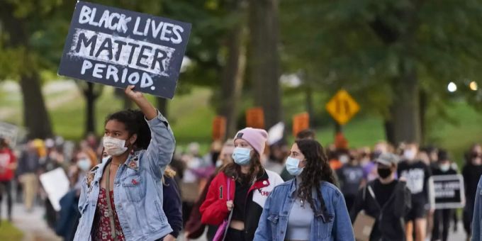 Eine junge Frau protestiert an einer Demonstration in Cleveland mit einem Schild gegen die Unterdrückung der schwarzen US-Bevölkerung. evanston reparationen good news