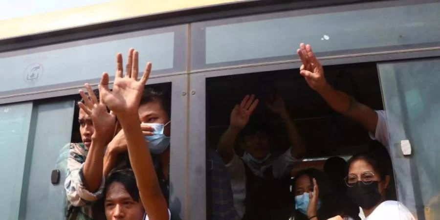 Festgenommene Demonstranten winken Menschen, während sie in einem Bus sitzen, der aus dem Insein-Gefängnis kommt und sie zu einem ungenannten Ort transportieren wird. Foto: Uncredited/AP/dpa
