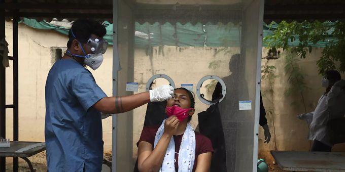 Ein Mitarbeiter des Gesundheitswesens entnimmt einer Frau in Indien einen Abstrich. Indien Coronavirus