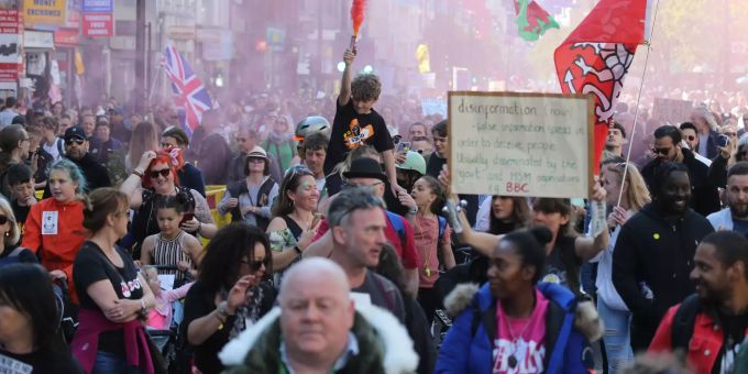 Demonstranten halten während des Unite For Freedom Protests Plakate und bengalische Feuer in die Höhe. Coronavirus London