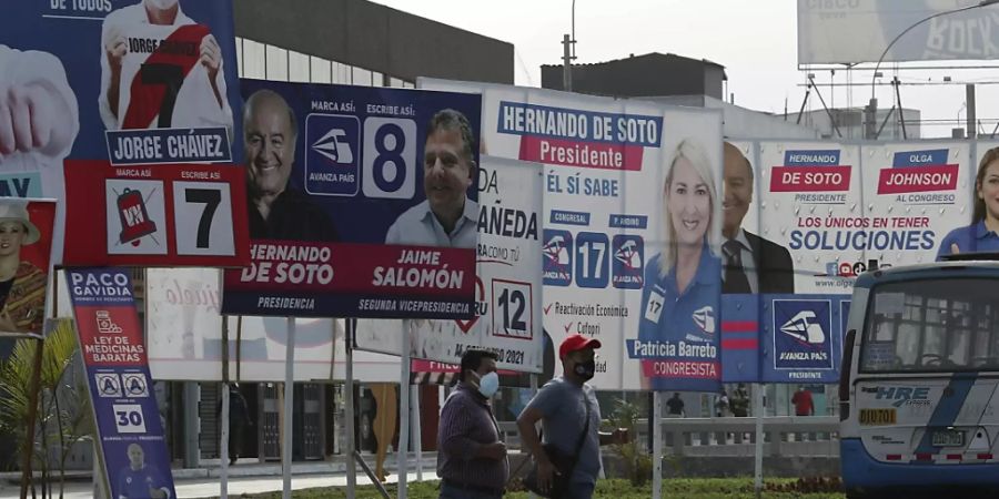 Menschen mit Mund-Nasen-Bedeckung überqueren eine Strasse, an der Wahlplakate der Präsidentschaftskandidaten hängen. Foto: Martin Mejia/AP/dpa