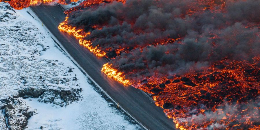 Glühende Lava fliesst über eine Strasse nach Grindavík.