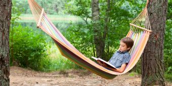 Kind mit Buch in Hängematte