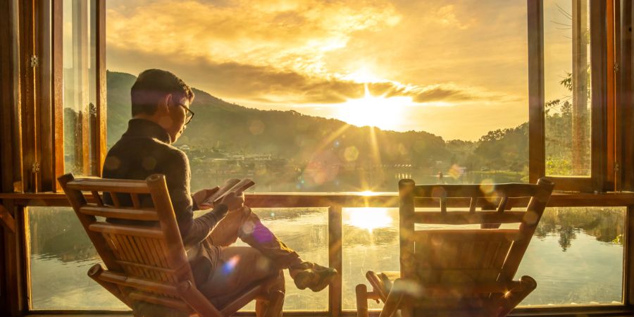 Mann auf Stuhl, Lesen, Sonne, Seeblick