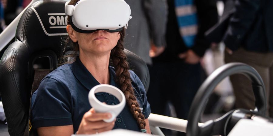 Eine Frau sitzt am Stand der Firma Siemens im vollelektrischen Fahrzeug SimRod.