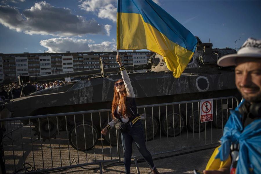 Eine Frau winkt in Prag mit einer ukrainischen Flagge vor einem zerstörten russischen Armeefahrzeug des Typs «2S34 Khosta» während der Eröffnung der Ausstellung russischer Militärausrüstung,