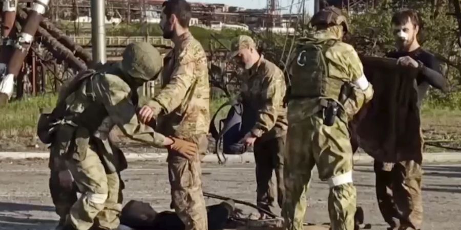 Russische Soldaten durchsuchen ukrainische Kämpfer, nachdem diese das Stahlwerk Asowstal verlassen haben.