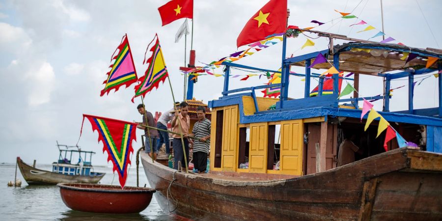 Einheimische Fischer und ältere Gläubige besteigen das Tempelboot im Rahmen des Walanbetungsfestes von Tam Hai.