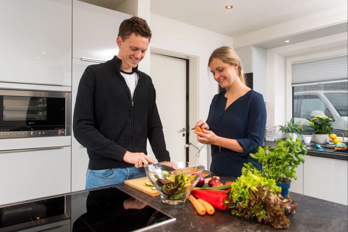 In einer sauberen Küche haben Bakterien beim Zubereiten der Lebensmittel keine Chance. Frau Mann Küche Schneidebrett Gemüse Salatschüssel