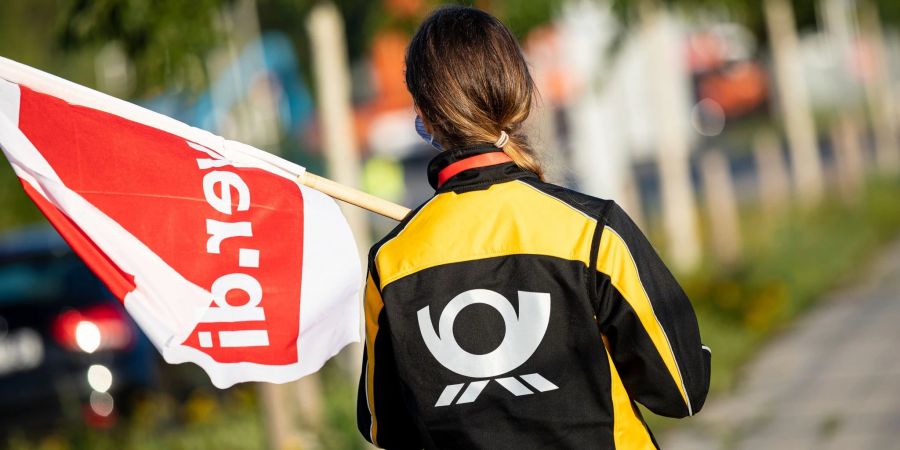 Eine Beschäftigte der Deutschen Post mit einer Fahne der Gewerkschaft Verdi vor einer Deutsche-Post-DHL-Niederlassung in Hannover.