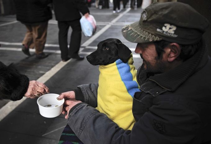 Ein Bettler hat seinen Hund warm eingepackt. hunde betteln