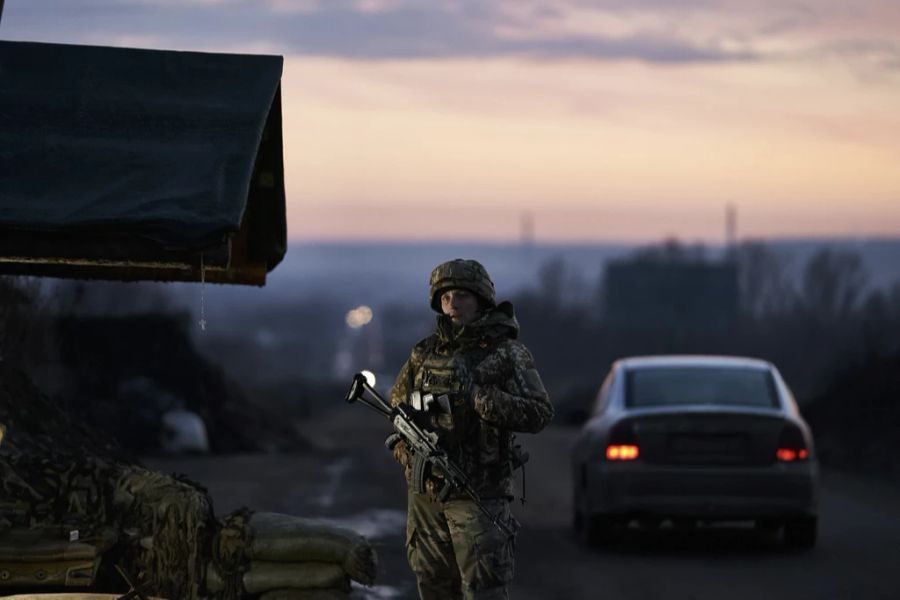 Ein ukrainischer Soldat steht an einem Kontrollpunkt, während die Sonne in Kramatorsk untergeht.