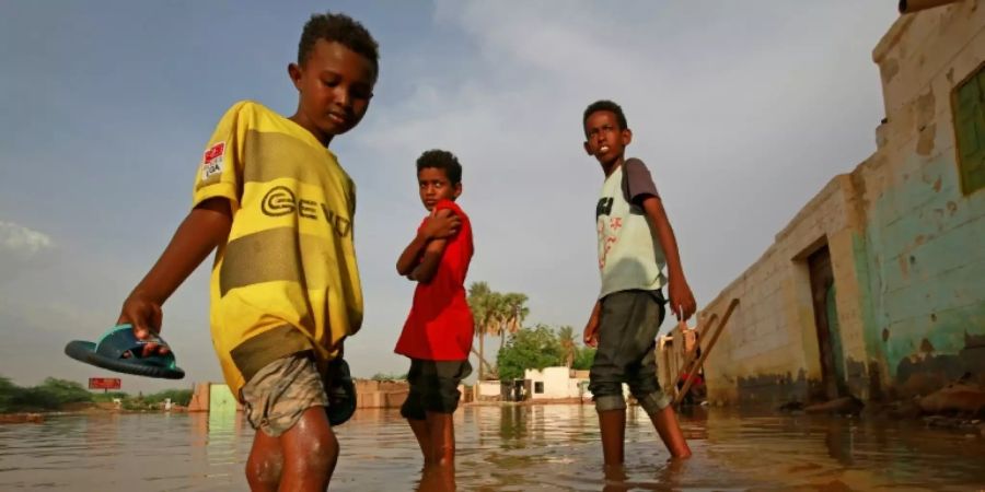 Sudanesische Jungs auf einer überschwemmten Strasse