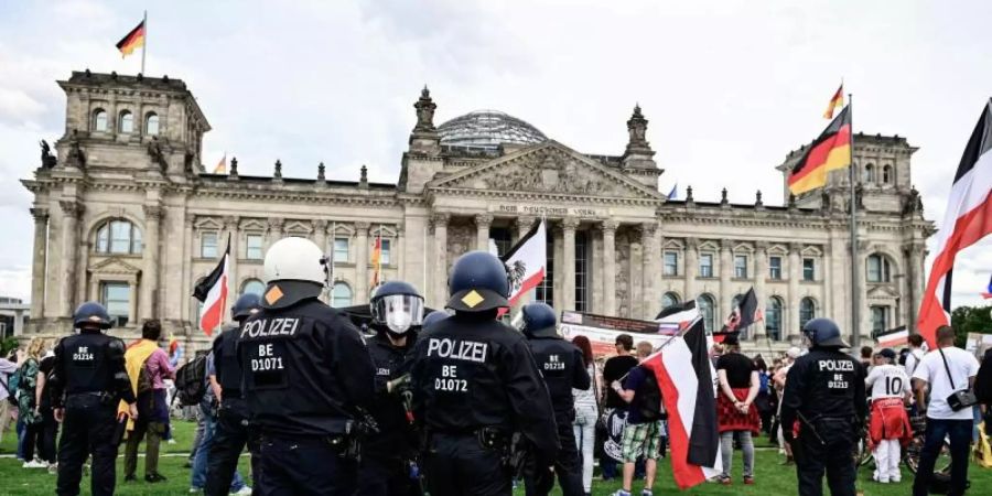 Teilnehmer einer Demonstration gegen die Corona-Massnahmen stehen mit Reichsflaggen in Berlin.