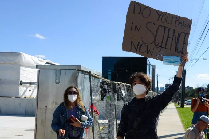 Ein junger Mann hält ein Schild "Do you believe in Science now" (Glaubst du jetzt an die Wissenschaft) vor dem Militärkrankenhaus Walter Reed in Bethesda. trump