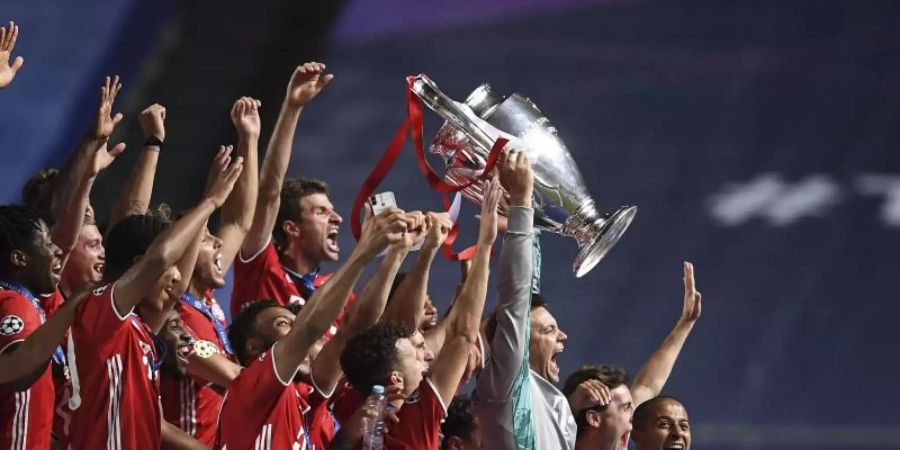 Bayerns Torhüter Manuel Neuer stemmt die Trophäe in die Höhe und jubelt mit dem Team. Foto: David Ramos/Pool Getty/AP/dpa