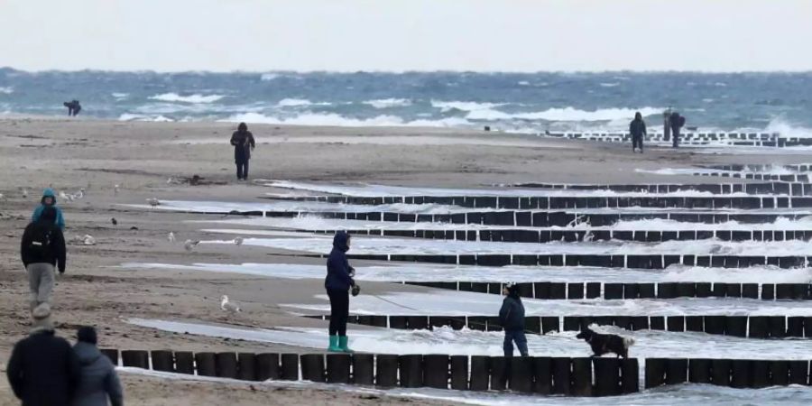 Spaziergänger sind am Strand bei Graal-Müritz unterwegs. Foto: Bernd Wüstneck/dpa-Zentralbild/dpa
