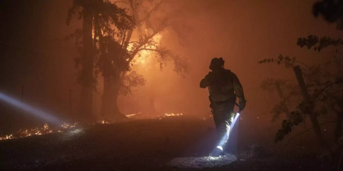Ein Feuerwehrmann geht neben einem brennenden Haus vorbei. (Archiv) Feuer