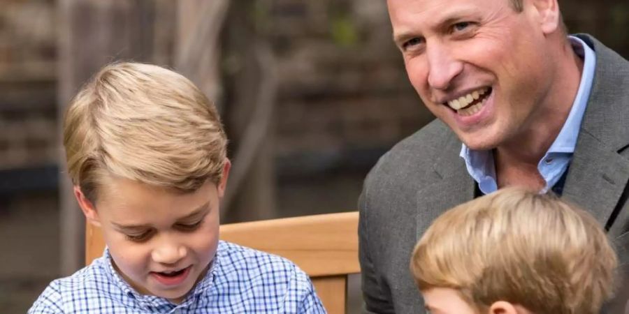 Prinz George (l) bestaunt sein Geschenk. Neben ihm sein Vater Prinz William und sein kleiner Bruder Prinz Louis (r). Foto: Kensington Palace/PA Wire/dpa