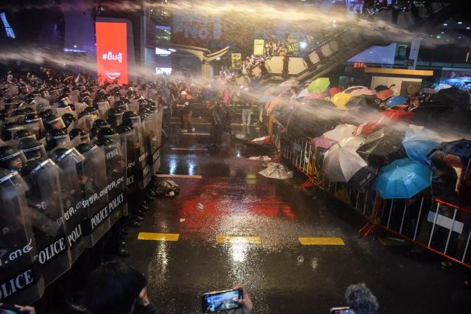Regierungskritische Demonstranten und Polizisten stehen sich bei einem Protest gegenüber während Wasserwerfer die Demonstranten versuchen auseinander zutreiben. In dem südostasiatischen Land gibt es seit Monaten Massendemonstrationen. Die Teilnehmer fordern den Rücktritt des Regierungschefs, eine Neuwahl und umfassende Reformen – auch für die Monarchie. Proteste in Bangkok