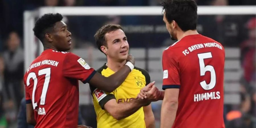 Münchens David Alaba (l) und Mats Hummels (r) trösten Dortmunds Mario Götze nach der Niederlage. Foto: Sven Hoppe/dpa