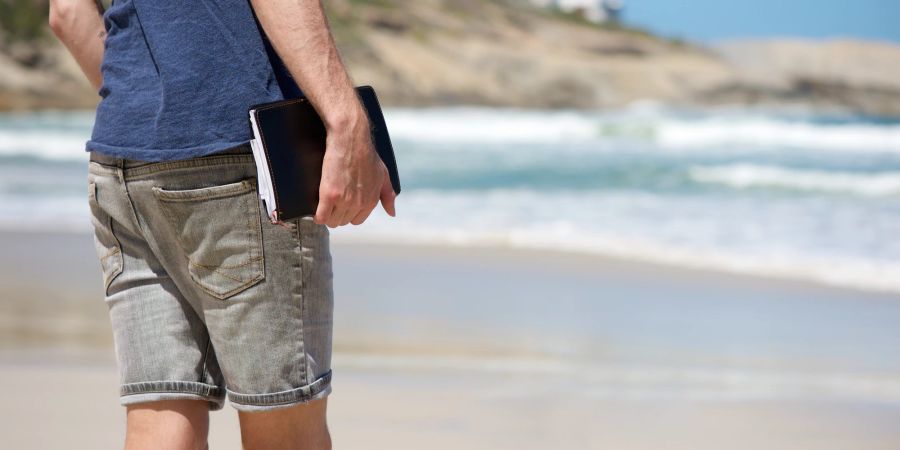 Mann mit Tagebuch am Strand.