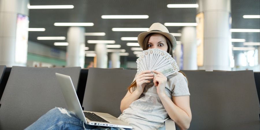 Frau am Flughafen mit Geldscheinen in der Hand.