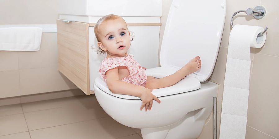 Kleines Mädchen sitzt in einer Toilette.