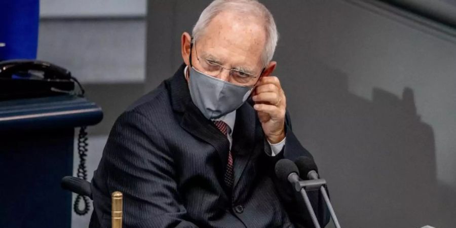Wolfgang Schäuble (CDU), Bundestagspräsident, nimmt vor der Regierungsbefragung seine Maske ab. Foto: Michael Kappeler/dpa