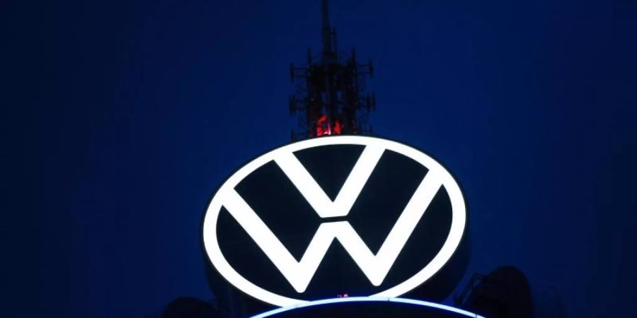 Das Volkswagen Logo leuchtet auf dem VW-Tower vor dunklem Himmel. Foto: Ole Spata/dpa