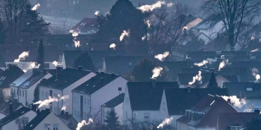 Schornsteine rauchen auf den Dächern der Häuser. Im Herbst sollen konkrete Massnahmen und Gesetze für mehr Klimaschutz kommen. Foto: Armin Weigel/Archiv