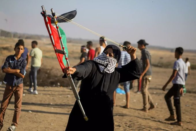 Eine palästinensische Demonstrantin wirft während eines Anti-Israel-Protestes am israelisch-gazaischen Grenzzaun im südlichen Gazastreifen mit einer Schleuder Steine. Anti-Israel-Demonstration in Gaza