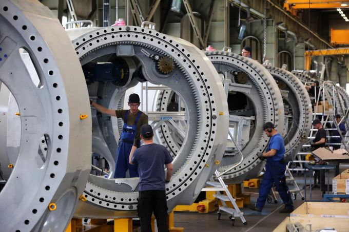 Mitarbeiter fertigen Rotornaben für Hochleistungsturbinen bei einem Windkraftanlagenbauer. Abwärtstrend hält an - Industrie bekommt weniger Aufträge