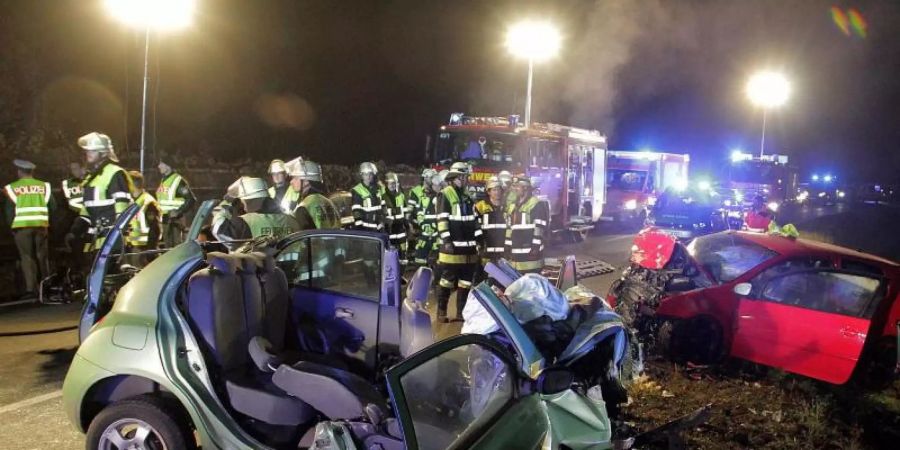 Raserunfall: Rettungskräfte und zwei zerstörte Fahrzeuge stehen an einer Unfallstelle. Foto: Josef Reisner/dpa/Archivbild