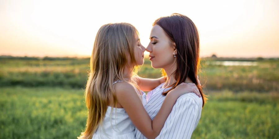 Mutter mit Tochter auf dem Arm Feld Sonnenuntergang