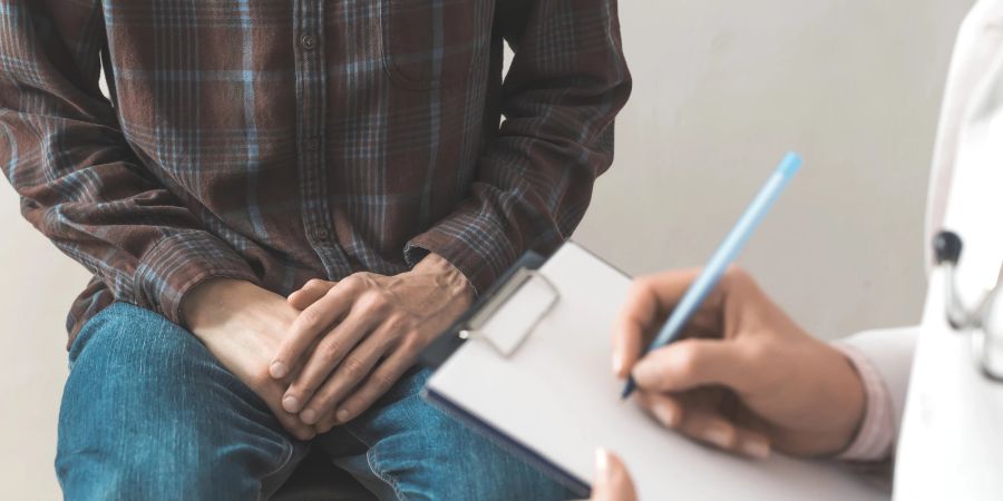 Der männliche Patient sitzt beim Arzt.